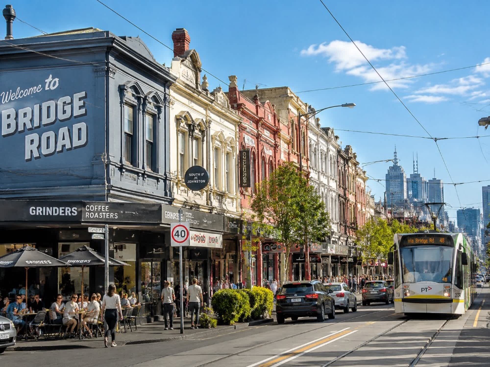 A street with buildings, a tram, and people.