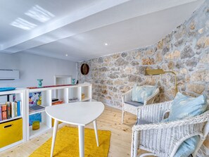 A cozy living room with a stone wall, a white sofa, a yellow rug, and a white table. - Vacation home Lemon by Interhome (Krk/Malinska)