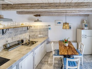 A kitchen with a wooden table, white cabinets, and a tiled backsplash. - Vacation home Lemon by Interhome (Krk/Malinska)