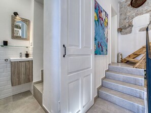 A modern bathroom with a white vanity, a mirror with an ornate frame, and a colorful abstract painting on the wall. - Vacation home Lemon by Interhome (Krk/Malinska)