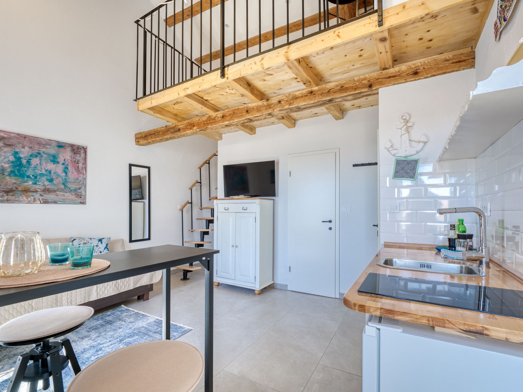 Eine moderne Küche mit Holzbalkendecke, ein Essbereich mit Tisch und Stühlen sowie eine Treppe zu einer oberen Ebene.