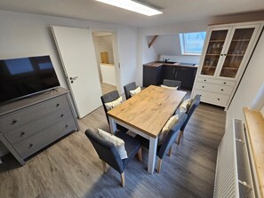 Eine moderne Küche mit Holztisch und -stühlen, einem eingebauten Backofen und einem Schrank mit Glastüren.