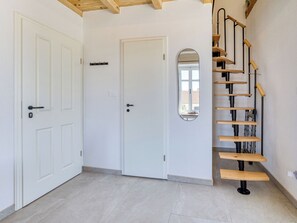 A room with a white door, a white wall, a mirror, and a wooden staircase. - Passion by Interhome (Krk/Malinska)