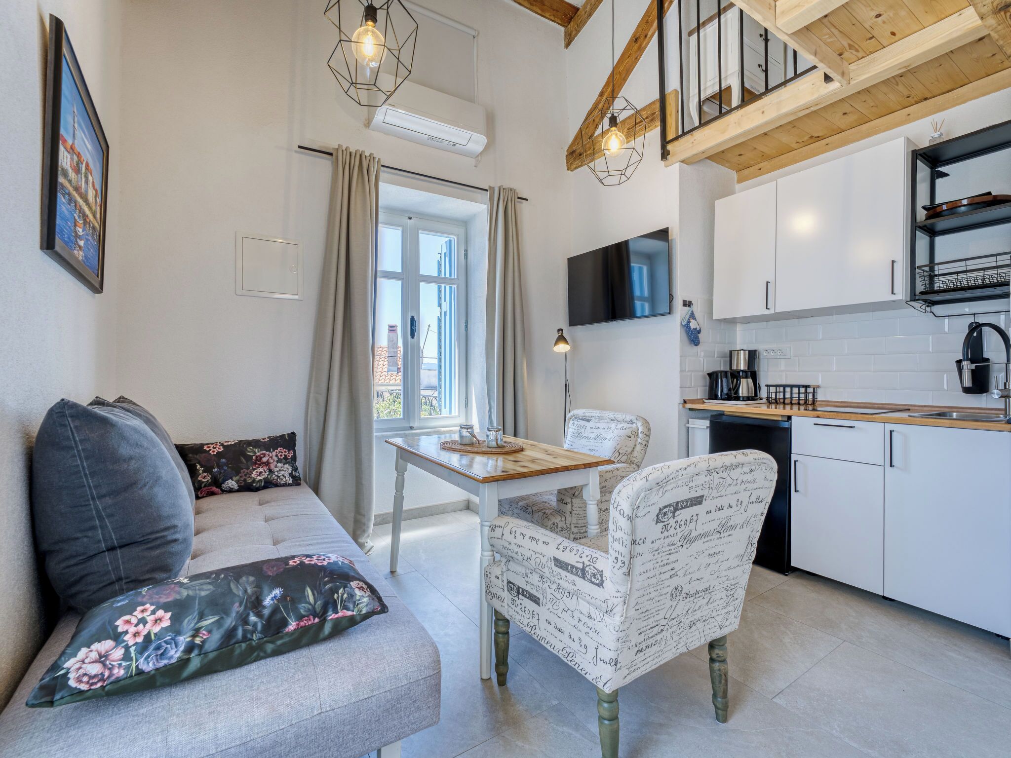 Una cocina moderna con comedor, un sofá con cojines estampados y una escalera.