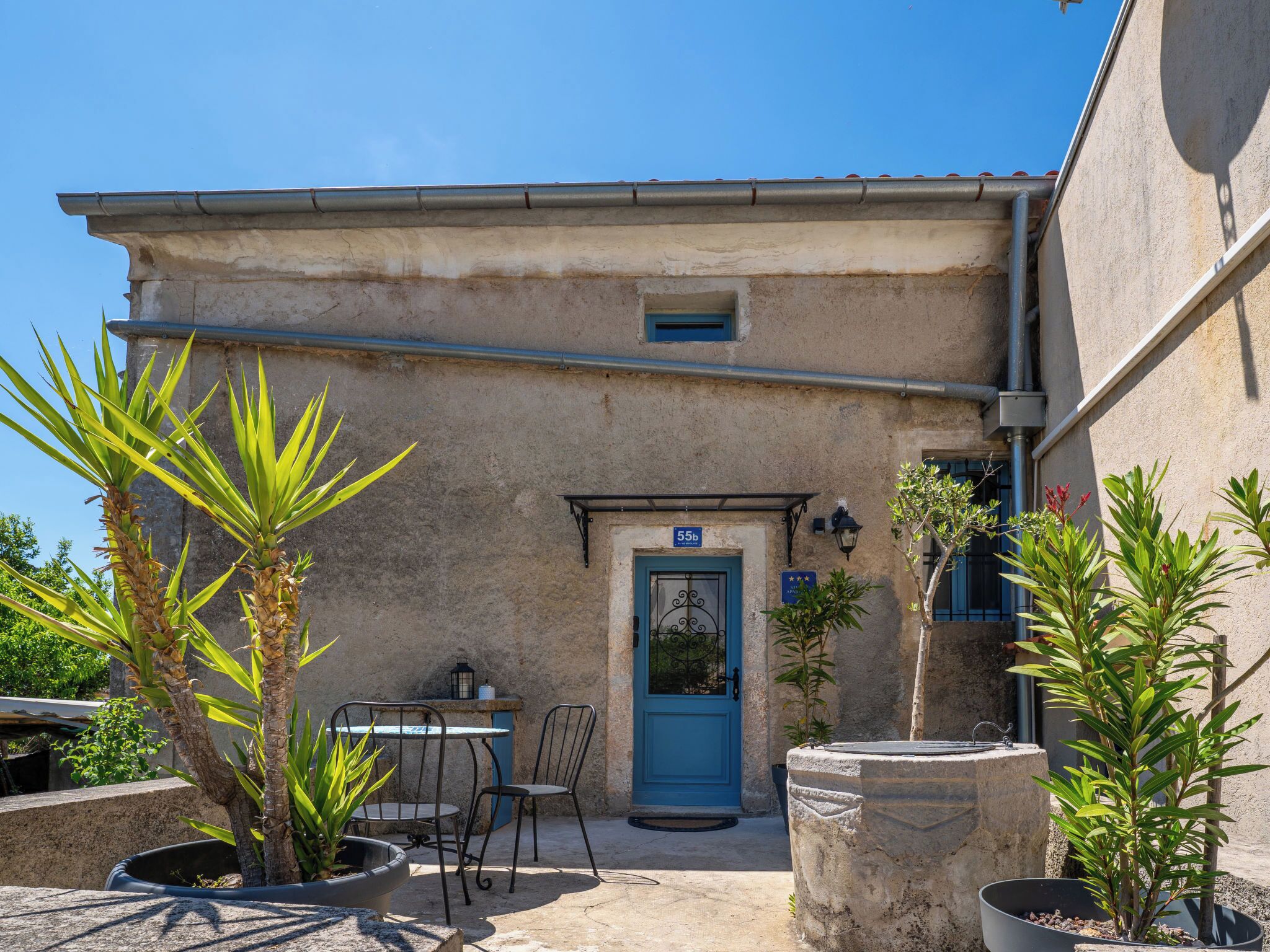A building with a blue door, outdoor seating, and potted plants.