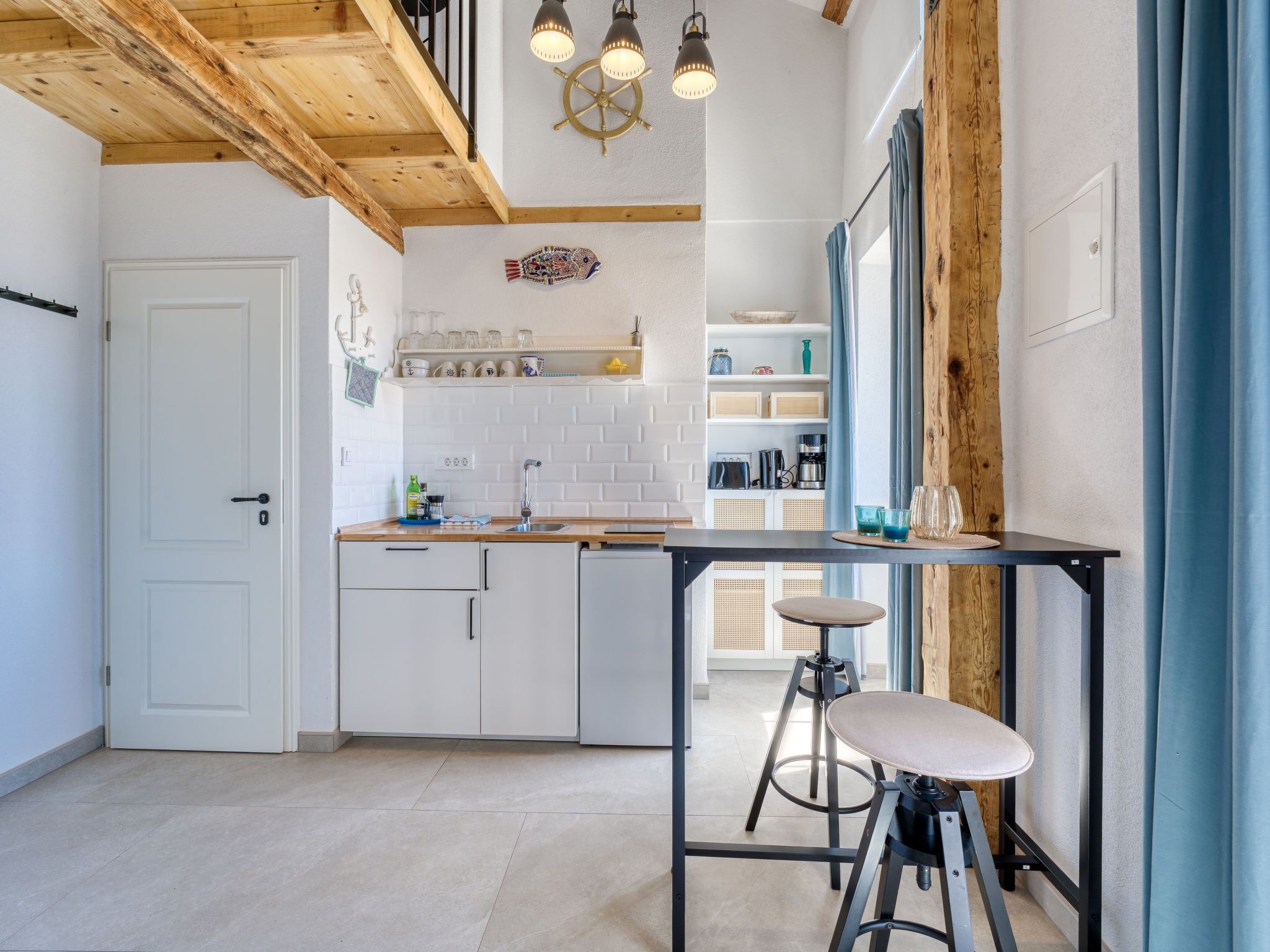 A modern kitchen with white cabinets, a wooden ceiling, and a bar area with stools.