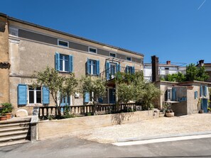 Ein Gebäude mit mehreren Fenstern, einem Balkon und einer kleinen Gartenanlage.