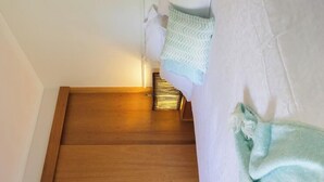 A bedroom with a wooden floor, a bed with white bedding, a green towel, and a white pillow. - All seasons for families
House on the hill 
NOW WITH  nbn, wi-fi and FOXTEL (Rosebud)