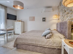 Une chambre à coucher avec un lit, une table de chevet, une lampe et un téléviseur fixé au mur.