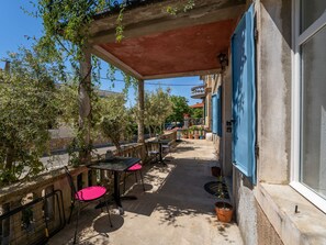 Eine Terrassenanlage mit Tischen, Stühlen und Pflanzen in Töpfen, teilweise überdacht.