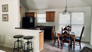 A kitchen with a refrigerator, a dining table with chairs, a bar stool, and a chandelier. - Charming 3-bedroom Monthly Rental Home in Mandeville (Mandeville)