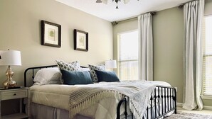 A neatly arranged bedroom with a bed, bedside tables, a floor lamp, and a ceiling fan. - Charming 3-bedroom Monthly Rental Home in Mandeville (Mandeville)