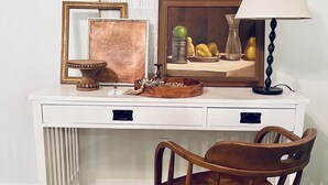 A white desk with a chair, a lamp, and framed artwork. - Charming 3-bedroom Monthly Rental Home in Mandeville (Mandeville)