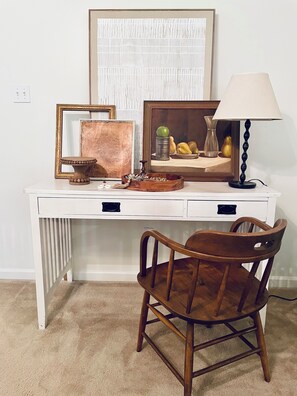A white desk with a chair, a lamp, and framed artwork. - Charming 3-bedroom Monthly Rental Home in Mandeville (Mandeville)