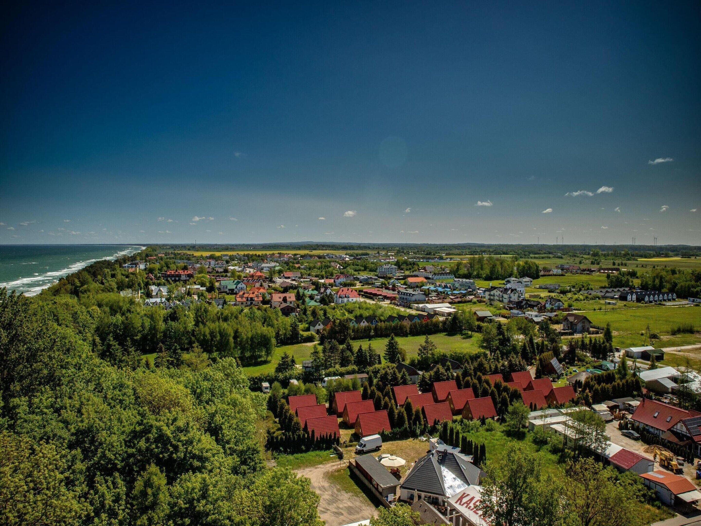 An aerial view of a coastal town with houses, a beach, and a clear sky.