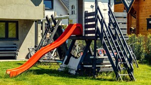 A playground with a slide and climbing structures, surrounded by houses with different architectural styles. - Two-story Holiday Homes With Terraces (Mielno)