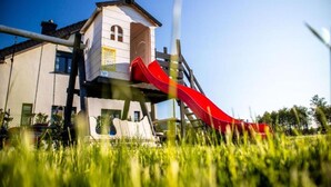 A playground with a red slide attached to a white building with a small tower-like structure. - Two-story Holiday Homes With Terraces (Mielno)