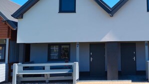 A modern two-story building with a white facade, a dark roof, and a small window on the upper floor. - Two-story Holiday Homes With Terraces (Mielno)