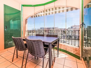 Ein Balkon mit Tisch und Stühlen, eine grüne Tür und Blick auf Gebäude.