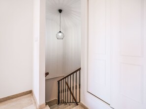 Eine Treppe mit hölzernem Geländer und Metallreling, die zu einer weißen Tür führt.