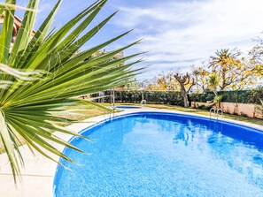 Une piscine à l’eau d’un bleu cristallin, entourée d’une pelouse bien entretenue et d’arbres.