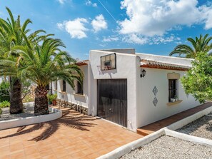 A white building with a black door, a basketball hoop, and palm trees. - El Refugio de Rembrandt by Interhome (Jávea)