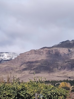 A mountainous landscape with a rocky cliff and sparse vegetation in the foreground.