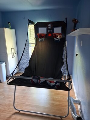 Una canasta de baloncesto con red, un equipo de aire acondicionado instalado en la pared y suelo de madera.