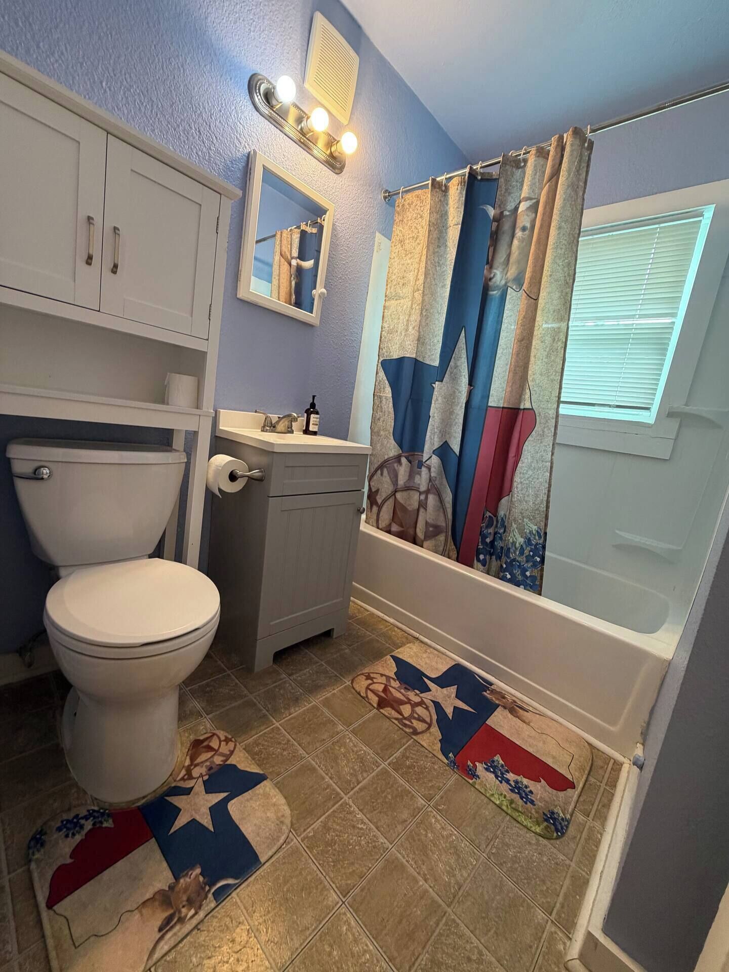 Een badkamer met toilet, wastafel, spiegel en douchegordijn.
