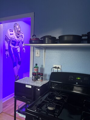 Una cocina con estufa a gas, horno empotrado y repisas con ollas.