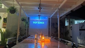 A conference room with a long table, hanging plants, and a screen displaying 'POP SONGS'. - Oceana surf Maldives - Kudahuvadhoo (Kudahuvadhoo,)