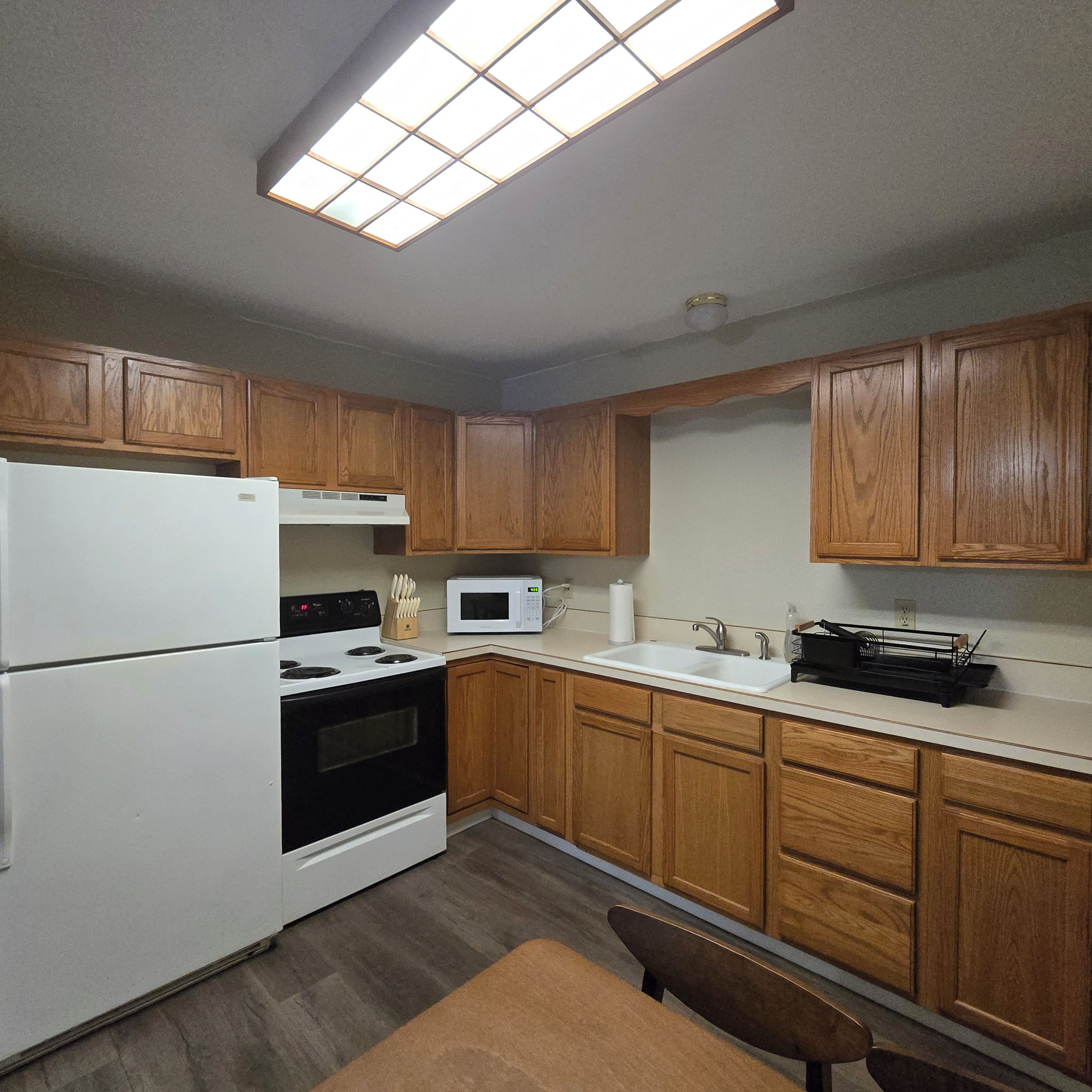 A kitchen with wooden cabinets, a white refrigerator, a stove, a microwave, and a sink.