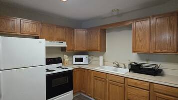 A kitchen with wooden cabinets, a white refrigerator, a stove, a microwave, and a sink.