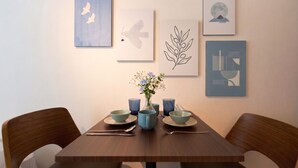 A dining table with a vase of flowers, two blue bowls, and a spoon. - Bellie Sangenjaya by Tranova 2 (Setagaya City)