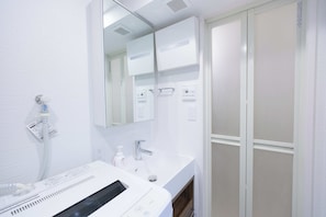 A modern bathroom with a white sink, a mirror, and a towel rack. - Bellie Sangenjaya by Tranova 2 (Setagaya City)