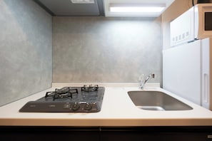 Una cocina con estufa a gas, un lavamanos y un microondas.