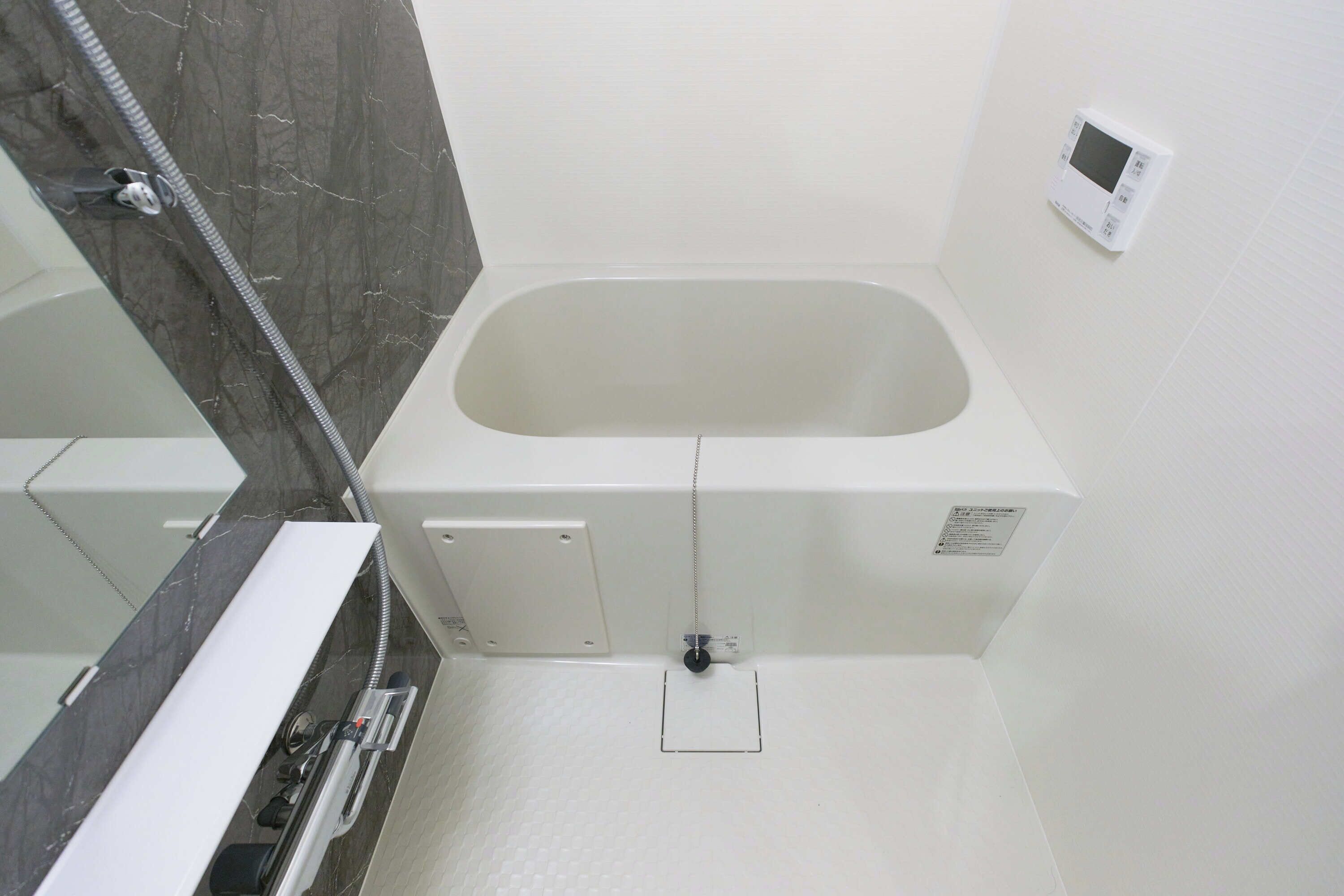 Une salle de bain équipée d’une baignoire, d’une douche, de toilettes et d’un panneau de commande mural.