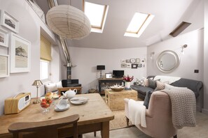 Ein gemütliches Wohnzimmer mit Kamin, einem Esstisch mit Frühstücksangeboten, einer Couch und einem Fernseher.