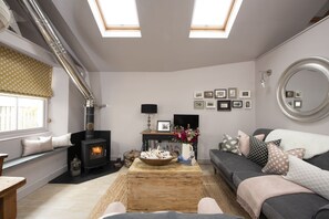 Ein gemütliches Wohnzimmer mit Kamin, Sofa, Couchtisch und Fernseher.