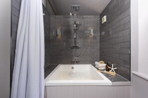 Un baño con ducha, bañera y paredes de azulejos.