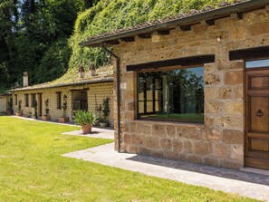 A stone building with a large window and a door, surrounded by a well-maintained lawn. - Villa La Grotta by Interhome (Acquapendente)