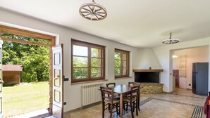 A kitchen with a dining table, chairs, a fireplace, and a refrigerator. - Villa La Grotta by Interhome (Acquapendente)