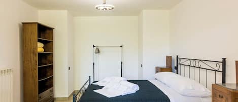 A bedroom with a bed, wooden wardrobe, radiator, and a ceiling light fixture.