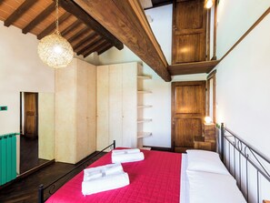 Een hotelkamer met een bed, een houten garderobe, een spiegel en een hanglamp.