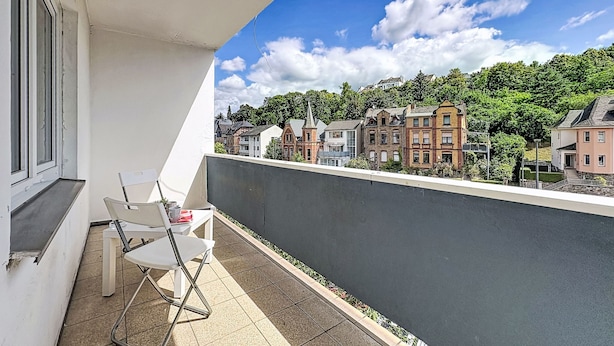 Ein Balkon mit Blick auf Gebäude und einen klaren Himmel.
