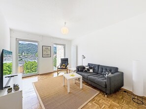 A spacious living room with a sofa, a small table, a chair, and a television. - Cozy Home Lahnstein by Interhome (Lahnstein (Koblenz))