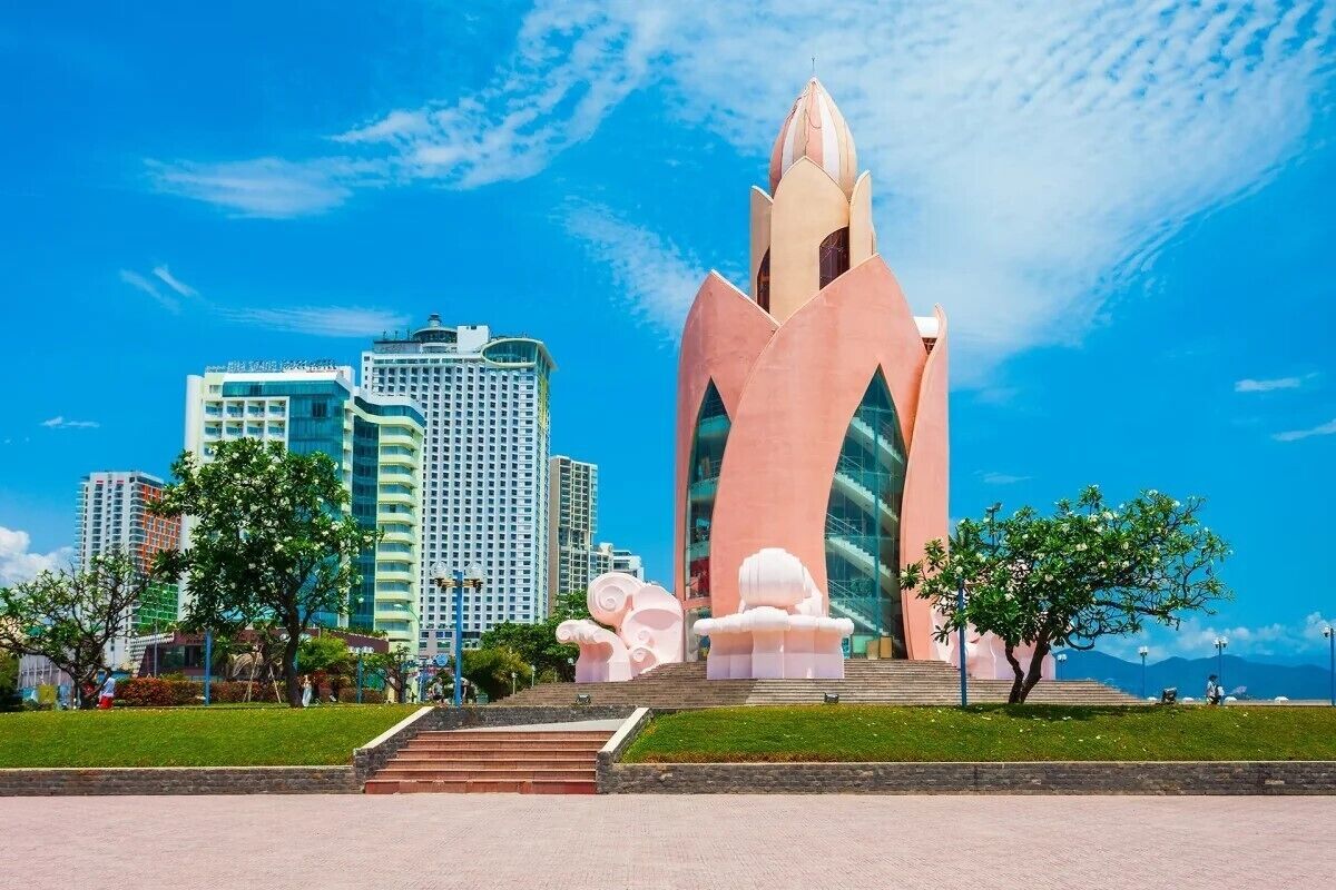 A modern building with a unique architectural design, surrounded by a well-maintained park and other high-rise buildings in the background.