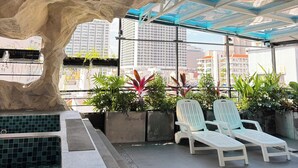 An outdoor lounge area with a rock-like structure, potted plants, and a pool. - Jolia Nha Trang Hotel (Nha Trang)