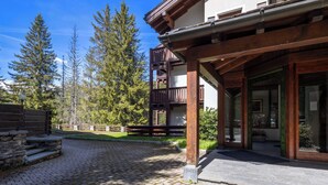 Ein Gebäude mit einem Holzbalkon, einem Steinweg und umliegenden Bäumen.