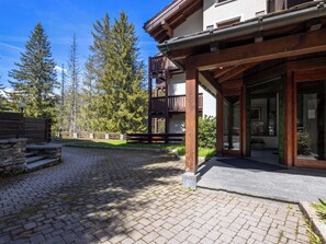 Ein Gebäude mit einem Holzbalkon, einem Steinweg und umliegenden Bäumen.